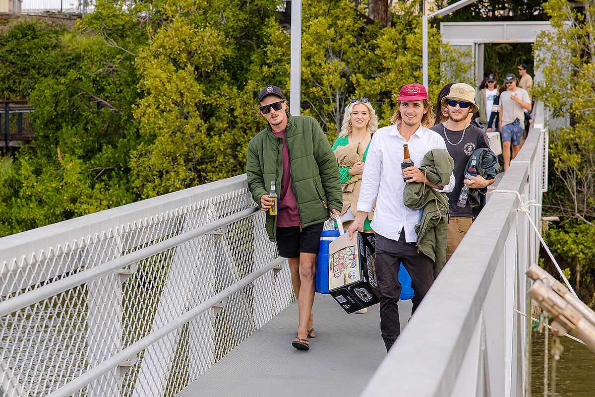 Large group of young people walk down ramp to board boat for river cruise party